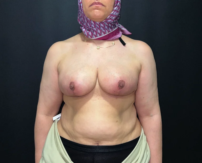 A woman with a bandana and necklace standing in front of a dark background.