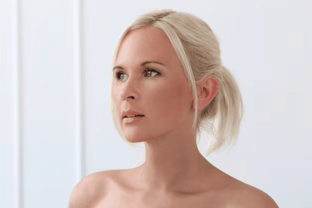 A blonde woman with her hair tied back, looking off to the side with a neutral expression.