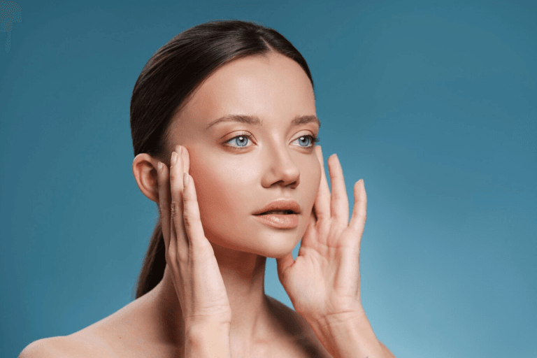 A young woman with clear skin touching her face, set against a blue background.