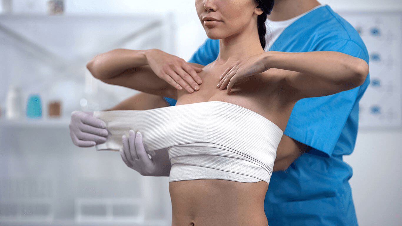 A doctor examining a patient's shoulder in a medical setting, applying a bandage to the patient's arm.