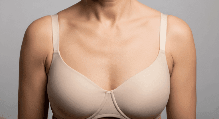 A woman wearing a beige bra with thin straps against a plain background.